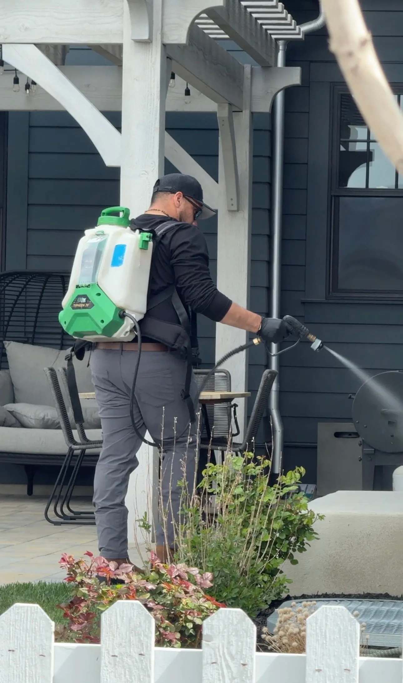 Technician with a backpack sprayer treating a home's front entry, Salt Lake City residential pest control