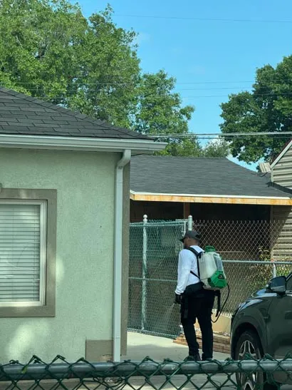 Bliss technician with a backpack sprayer treating a backyard beside the garage, Salt Lake City, UT