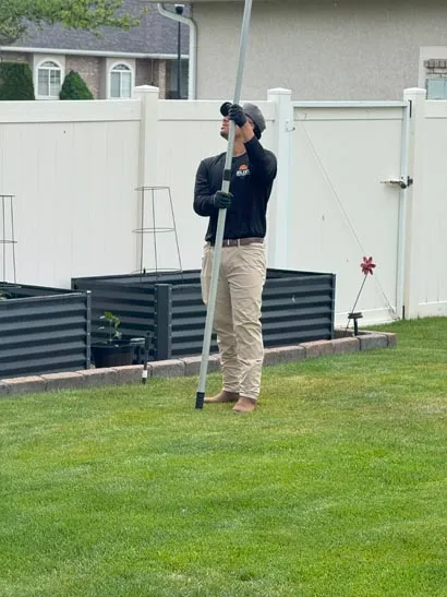 Technician treating eaves along a backyard fence line, Bliss Pest Services, Salt Lake City