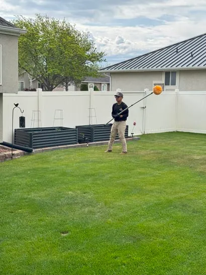 Salt Lake City exterminator treating a backyard roofline with an extension pole