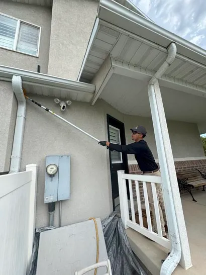 Salt Lake City pest control technician treating eaves above a side entry with an extension wand