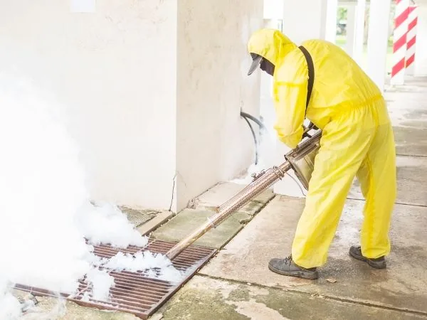 Exterminator in a yellow protective suit treating a building, commercial pest control in Salt Lake City